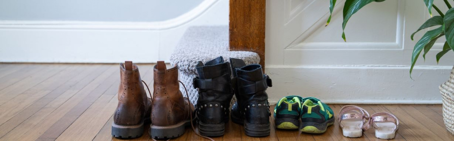 Family of four shoes lined up at foot of staircase.